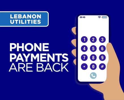 Hand holding a smartphone with a dial pad and the text Lebanon Utilities – Phone Payments Are Back.